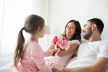 Image showing happy girl giving flowers to mother in bed at home