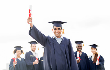 Image showing happy students in mortar boards with diplomas