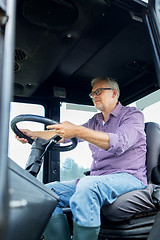 Image showing senior man driving tractor at farm