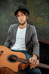 Image showing Cool guy sitting with guitar on gray background