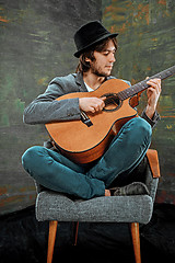 Image showing Cool guy with hat playing guitar on gray background