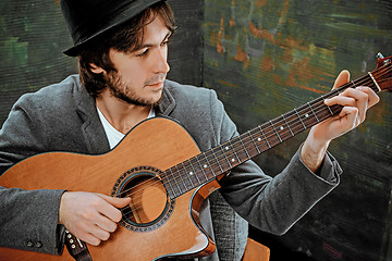 Image showing Cool guy with hat playing guitar on gray background