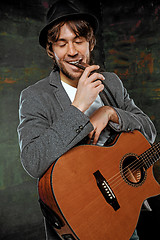 Image showing Cool guy with hat playing guitar on gray background