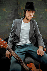 Image showing Cool guy sitting with guitar on gray background