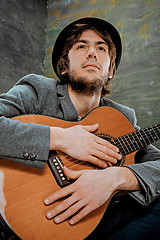 Image showing Cool guy sitting with guitar on gray background