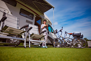 Image showing Woman is standing with a mug of coffee near the camper.