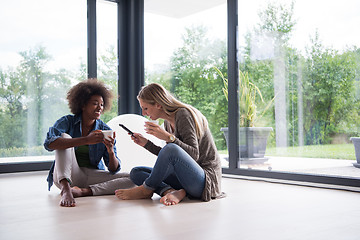 Image showing multiethnic women sit on the floor and drinking coffee