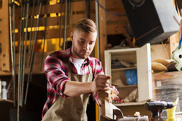 Image showing carpenter working with plane and wood at workshop