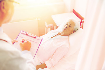 Image showing senior woman and doctor with clipboard at hospital