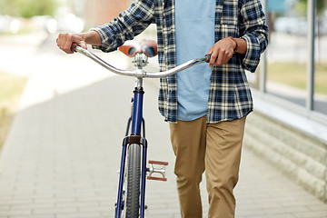Image showing close up of man with bicycle walking along city