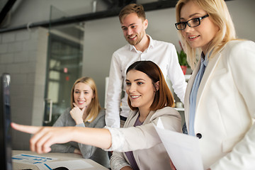 Image showing happy creative team with computer in office