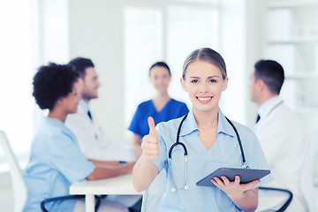 Image showing happy doctor with tablet pc over team at clinic