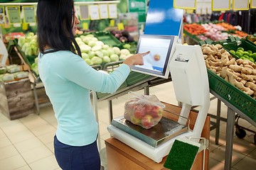 Image showing woman weighing apples on scale at grocery store