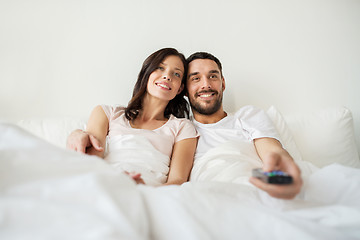 Image showing happy couple lying in bed at home and watching tv