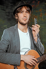 Image showing Cool guy with hat playing guitar on gray background