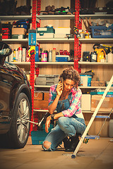 Image showing beautiful woman in blue overalls mechanic near the car and talki