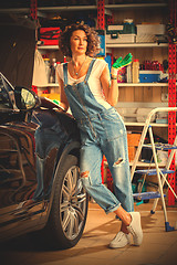 Image showing smiling woman car mechanic with the instructions in blue overall