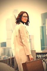 Image showing businesswoman with wooden case standing on background of busines