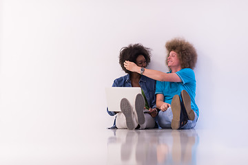 Image showing multiethnic couple sitting on the floor with a laptop and tablet