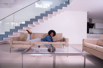 Image showing African American woman using laptop on sofa