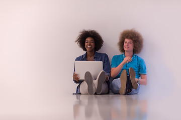 Image showing multiethnic couple sitting on the floor with a laptop and tablet