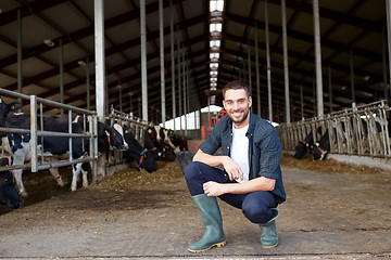 Image showing man or farmer with cows in cowshed on dairy farm