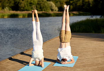 Image showing couple making yoga headstand on mat outdoors