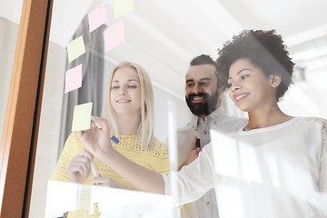 Image showing happy creative team writing on stickers at office