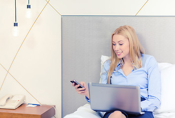 Image showing happy businesswoman with smartphone in hotel room