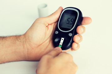 Image showing close up of man checking blood sugar by glucometer