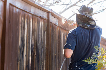 Image showing Professional Painter Spraying Yard Fence with Stain