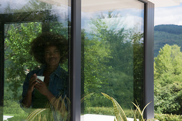 Image showing African American woman drinking coffee looking out the window