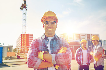 Image showing group of smiling builders in hardhats outdoors