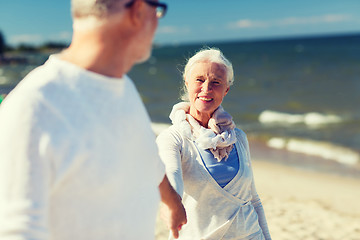 Image showing happy senior couple holding hands on summer beach