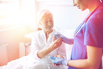 Image showing nurse giving medicine to senior woman at hospital