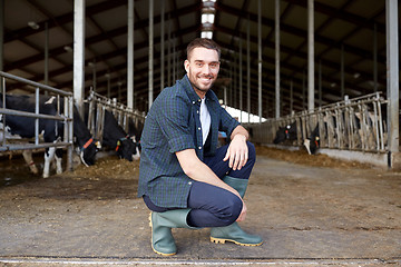 Image showing man or farmer with cows in cowshed on dairy farm