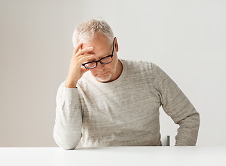 Image showing sad senior man sitting at table