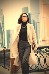 Image showing beautiful businesswoman in a light coat, with a wooden case and 