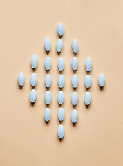 Image showing blue pills on beige background