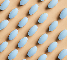 Image showing blue pills on beige background