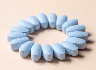 Image showing blue pills on beige background