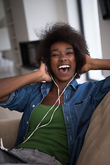 Image showing African american woman at home in chair with tablet and head pho