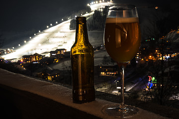 Image showing Glass and bottle with craft beer on a balcony at skiing village