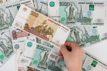 Image showing Children\'s hand takes the denomination from the pile of randomly scattered Russian banknotes of different denomination