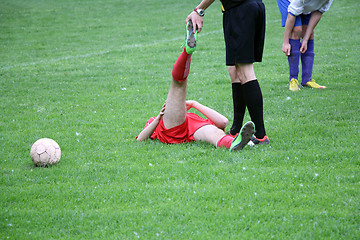 Image showing Referee provides assistance injured player at the football match