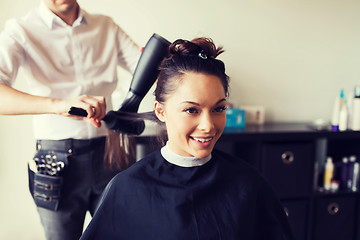 Image showing happy woman with stylist making hairdo at salon