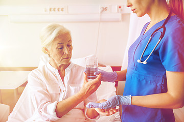 Image showing nurse giving medicine to senior woman at hospital