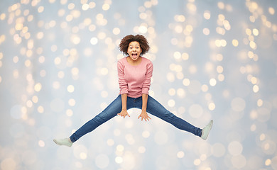 Image showing happy african american woman jumping over white