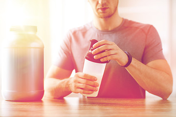 Image showing close up of man with protein shake bottle and jar