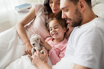 Image showing happy child with toy and parents in bed at home